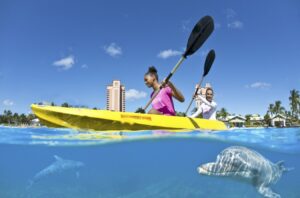 A woman is kayaking in the ocean with another person.