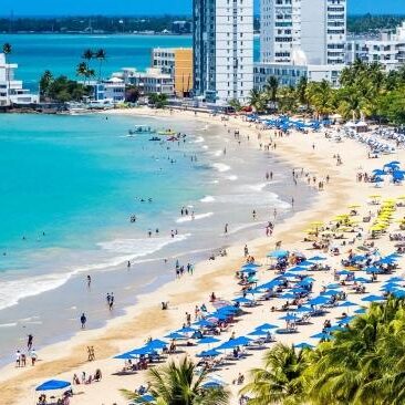 A beach with many people on it and some buildings