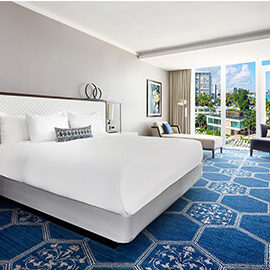 A bedroom with blue carpet and white furniture.